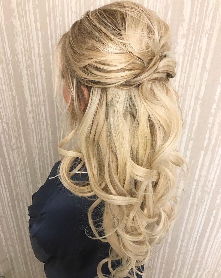 Long blonde curls styled in a loose half-up finish